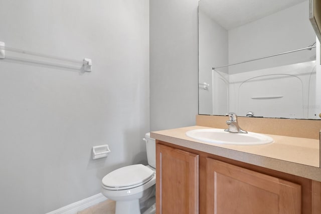 bathroom featuring walk in shower, toilet, vanity, and baseboards