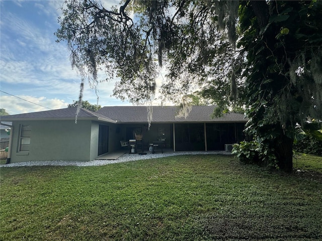 rear view of property with a yard, a patio, and a sunroom