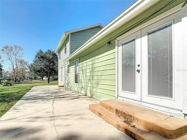 property entrance with a lawn and a patio area