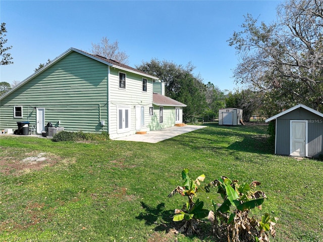 back of house with a lawn, a patio area, and a shed