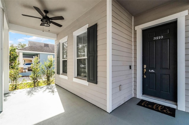 view of exterior entry featuring ceiling fan and a porch