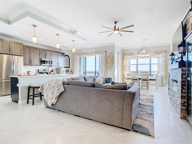 living room featuring ceiling fan with notable chandelier, plenty of natural light, and a fireplace