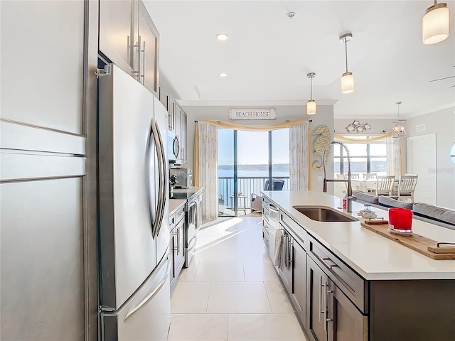 kitchen with stainless steel appliances, hanging light fixtures, a water view, dark brown cabinetry, and sink