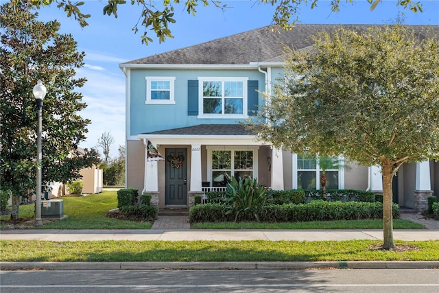 view of front of home featuring a shingled roof, a front yard, central air condition unit, and stucco siding