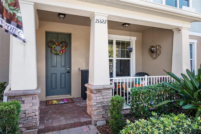 entrance to property featuring covered porch and stucco siding