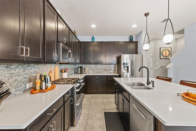 kitchen with sink, tasteful backsplash, light tile patterned floors, stainless steel appliances, and a kitchen island with sink