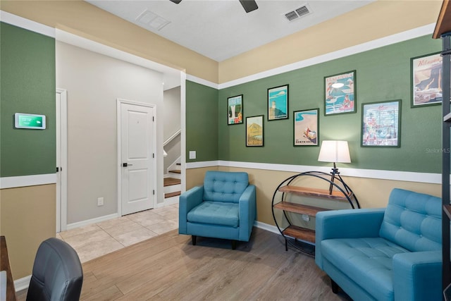 living area featuring visible vents, baseboards, ceiling fan, stairway, and wood finished floors