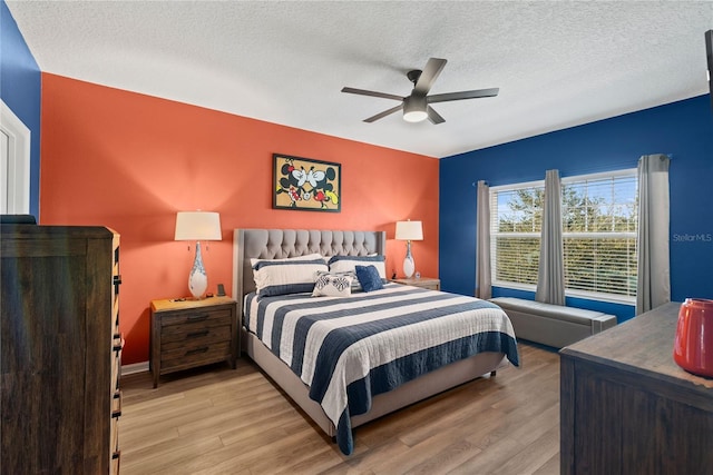 bedroom with light wood-style floors, a textured ceiling, baseboards, and a ceiling fan