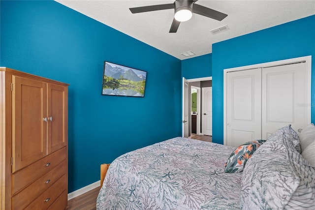 bedroom with baseboards, visible vents, a ceiling fan, wood finished floors, and a closet