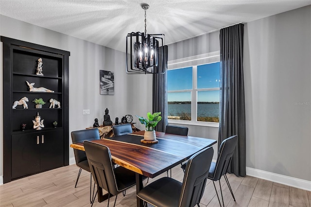 dining area featuring a textured ceiling, built in features, a notable chandelier, and a water view