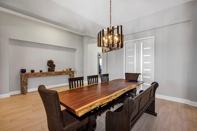 dining space with light hardwood / wood-style floors and a notable chandelier