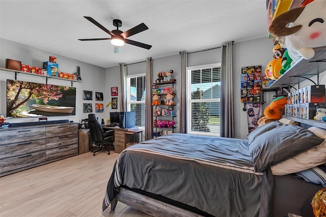 bedroom featuring light wood-type flooring, ceiling fan, and a textured ceiling