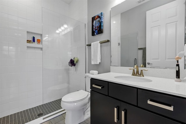 bathroom with toilet, tile patterned floors, tiled shower, and vanity