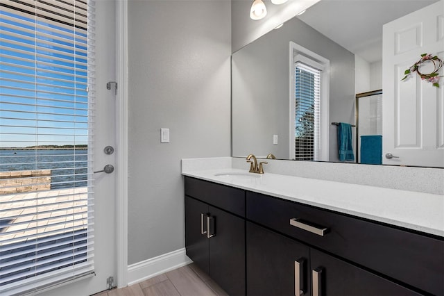 bathroom with a shower with door, a water view, and vanity