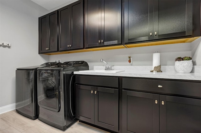 laundry room featuring washing machine and dryer, cabinets, light hardwood / wood-style flooring, and sink