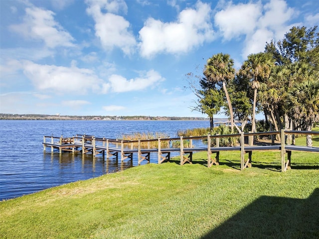 view of dock with a lawn and a water view