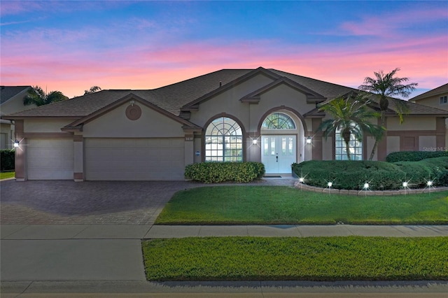 view of front of property featuring french doors, a yard, and a garage