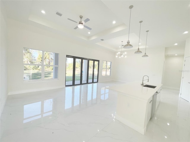 kitchen with visible vents, a kitchen island with sink, a sink, a raised ceiling, and open floor plan