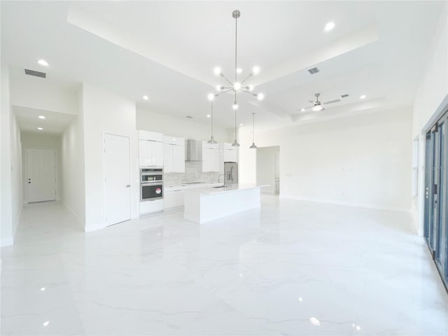 unfurnished living room featuring a sink, a tray ceiling, marble finish floor, and visible vents