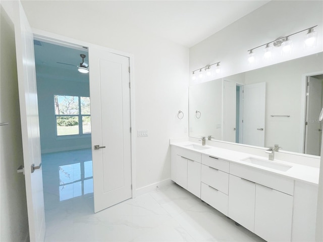 full bath featuring double vanity, marble finish floor, baseboards, and a sink