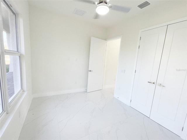 unfurnished bedroom featuring visible vents, baseboards, ceiling fan, a closet, and marble finish floor