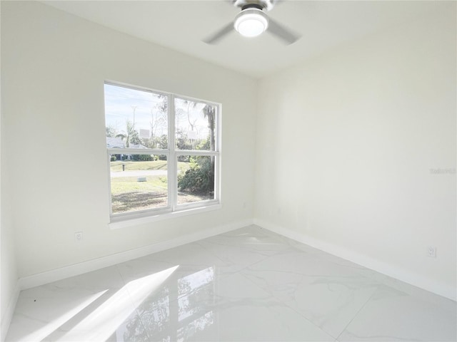 unfurnished room featuring a ceiling fan, baseboards, and marble finish floor