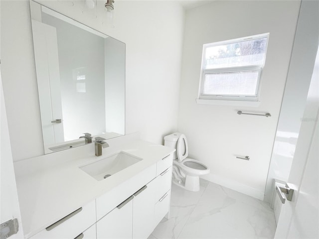 bathroom featuring vanity, toilet, baseboards, and marble finish floor