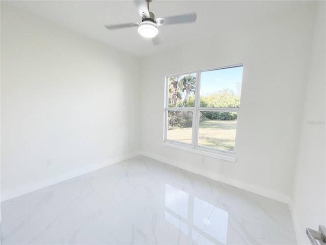 spare room featuring baseboards, marble finish floor, and a ceiling fan