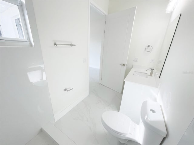 bathroom with double vanity, marble finish floor, toilet, and a sink