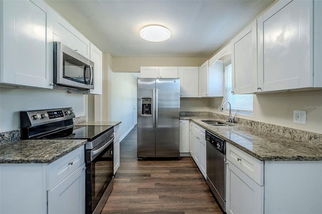 kitchen featuring appliances with stainless steel finishes, white cabinetry, dark stone counters, and sink