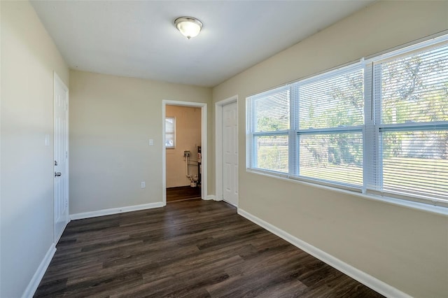 empty room featuring dark wood-type flooring and a healthy amount of sunlight