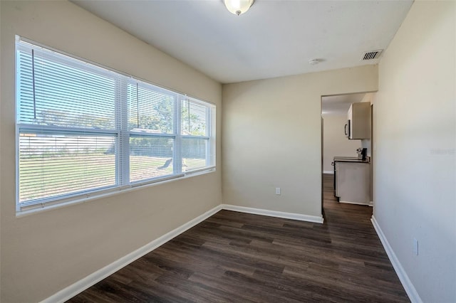 empty room featuring dark hardwood / wood-style flooring and a healthy amount of sunlight