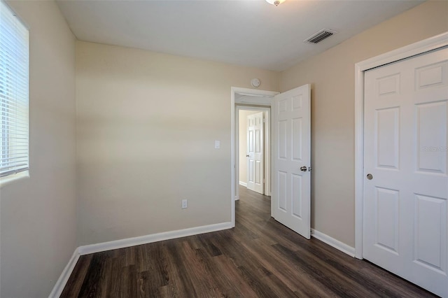 unfurnished bedroom with a closet and dark hardwood / wood-style flooring