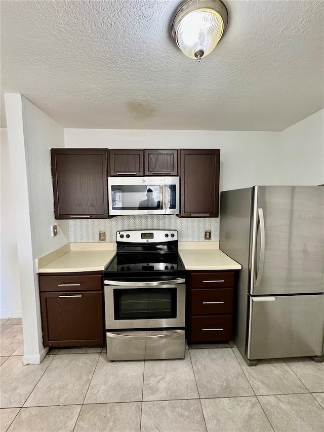 kitchen featuring dark brown cabinets, light tile patterned floors, and stainless steel appliances