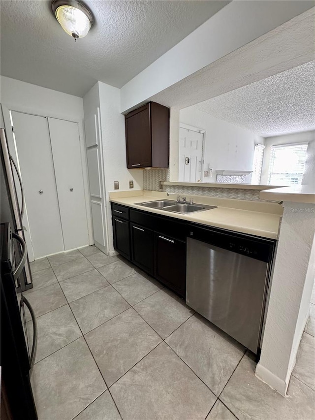 kitchen with dark brown cabinets, a textured ceiling, stainless steel dishwasher, and sink