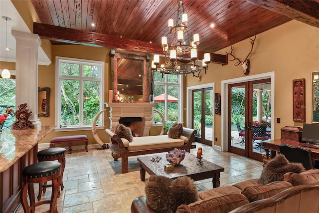 living area featuring decorative columns, french doors, beamed ceiling, and a notable chandelier