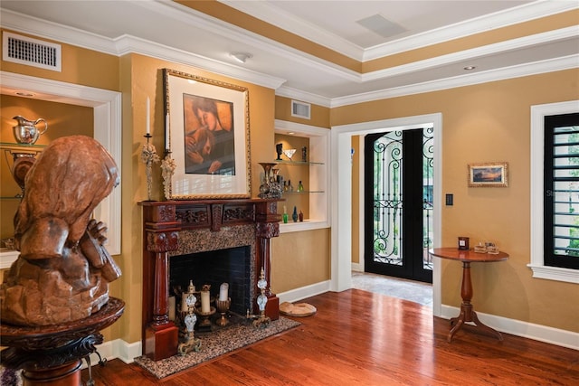 foyer featuring hardwood / wood-style flooring, a premium fireplace, and crown molding