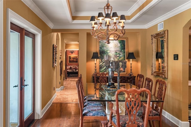 dining space with french doors, ornamental molding, a raised ceiling, a notable chandelier, and hardwood / wood-style floors