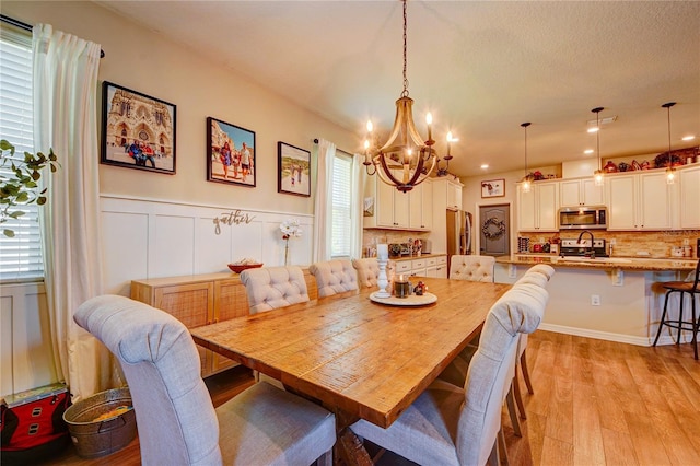 dining room with a notable chandelier, sink, and light hardwood / wood-style flooring