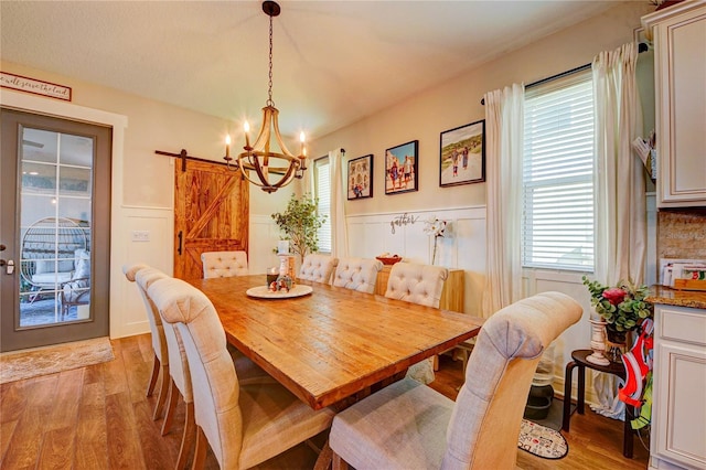 dining space with a barn door, light hardwood / wood-style floors, an inviting chandelier, and a wealth of natural light