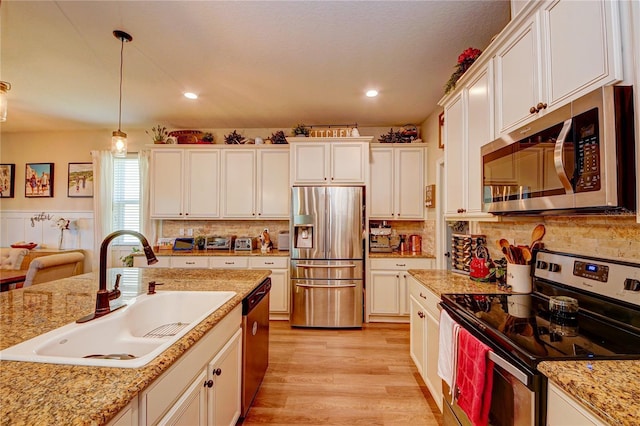 kitchen with white cabinets, pendant lighting, stainless steel appliances, and sink