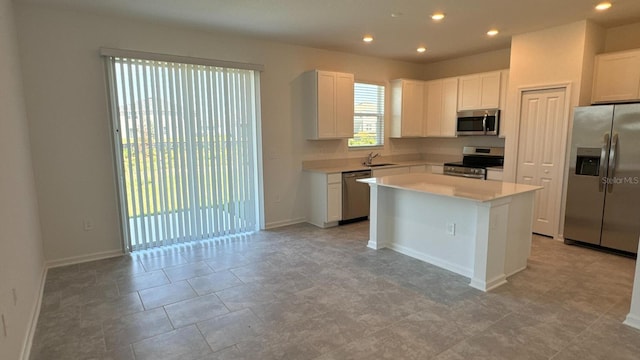 kitchen featuring a center island, white cabinets, stainless steel appliances, and sink