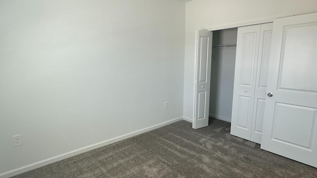 unfurnished bedroom featuring a closet and dark colored carpet