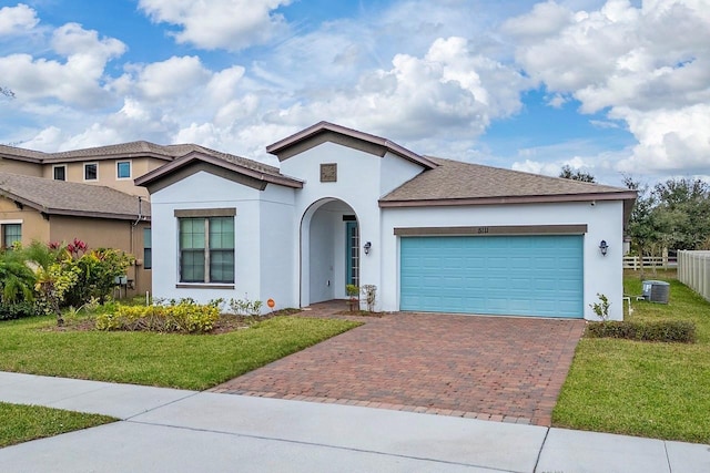 view of front of home featuring central AC, a garage, and a front lawn