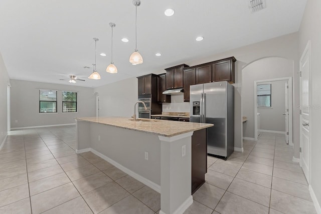 kitchen featuring ceiling fan, stainless steel fridge, dark brown cabinetry, and an island with sink