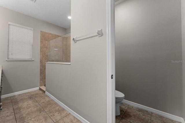 bathroom with tiled shower, tile patterned floors, vanity, and toilet