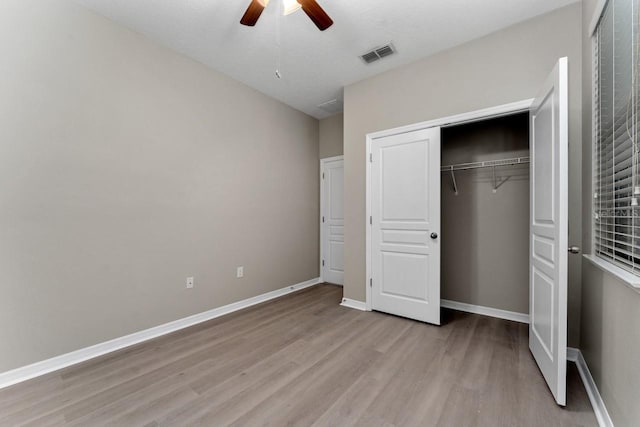 unfurnished bedroom with ceiling fan, a closet, and light wood-type flooring