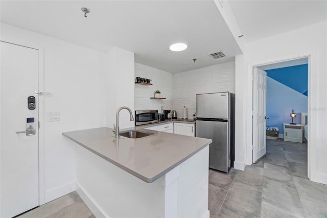 kitchen with kitchen peninsula, appliances with stainless steel finishes, white cabinetry, and sink