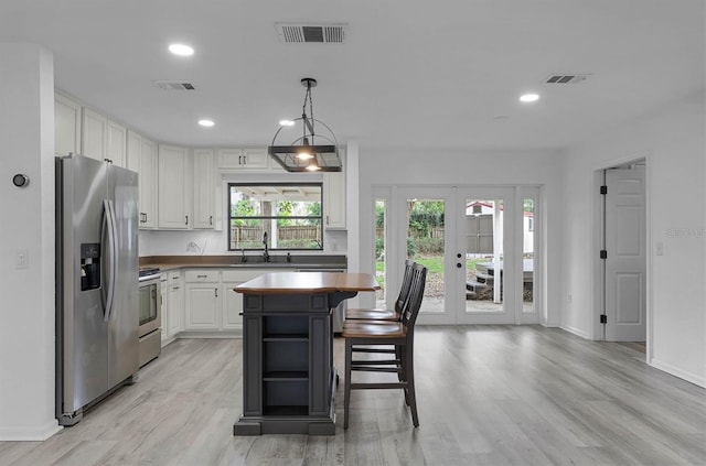 kitchen with a center island, stove, wooden counters, stainless steel refrigerator with ice dispenser, and white cabinetry