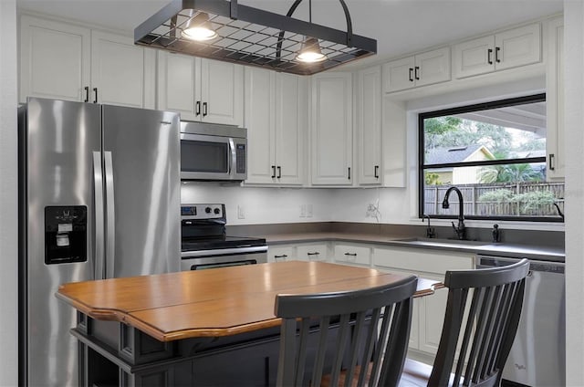 kitchen with hanging light fixtures, white cabinetry, sink, and appliances with stainless steel finishes